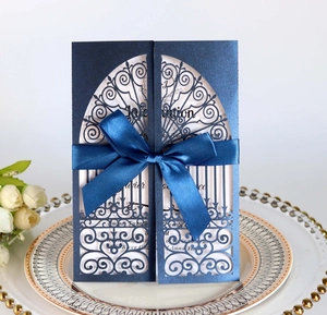 Detail of laser-cut navy blue wedding invitation with elegant satin bow and ribbon