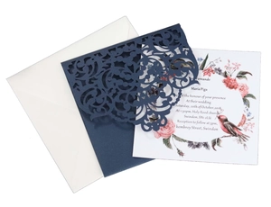Detail of laser-cut navy blue wedding invitation with intricate floral lace and inner card