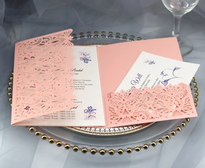 Detail of pink laser-cut wedding invitation with elegant floral insert and lace pattern