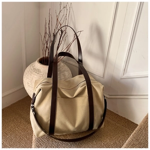 Detail of canvas tote bag with brown leather handles and adjustable shoulder strap