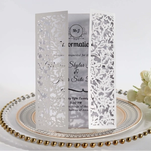 Elegant white laser cut wedding invitation card with intricate leaf pattern on ceramic plate