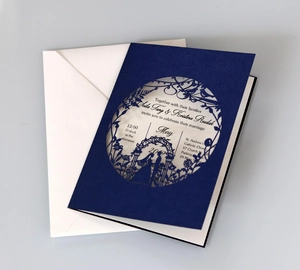 Detailed laser-cut navy blue wedding invitation cover with intricate nature and couple silhouette