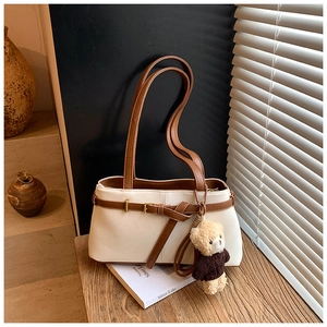 Detailed close-up of cream retro shoulder bag with leather buckles and plush bear charm
