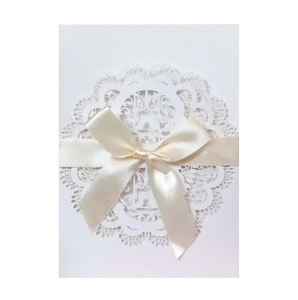 Elegant off-white laser-cut wedding invitation card with intricate lace bird patterns and bow