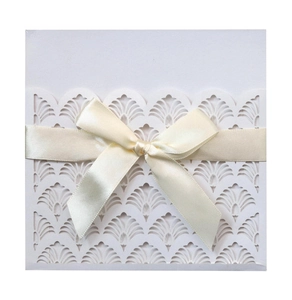 Elegant laser-cut lace wedding invitation card in ivory with a satin ribbon bow