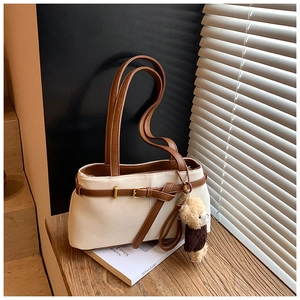Detailed view of matte cream leopard bucket bag with brown strap and teddy bear charm