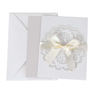 Close-up of laser-cut lace wedding invitation with white satin ribbon and intricate patterns