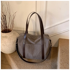 Detail of grey canvas tote bag with brown leather handles placed on carpet steps