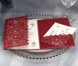 Macro detail of burgundy laser cut wedding invitation with intricate floral lace pattern