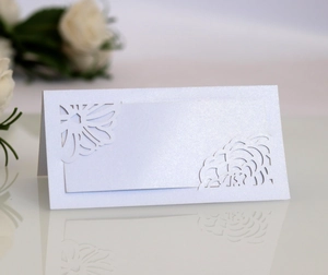 Close-up of laser-cut floral lace pattern on pearlescent white wedding table seating card