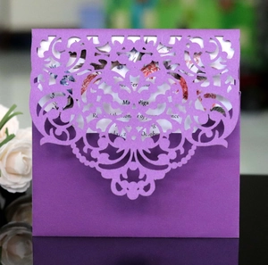 Close-up of purple laser-cut lace invitation card with elegant floral scroll patterns