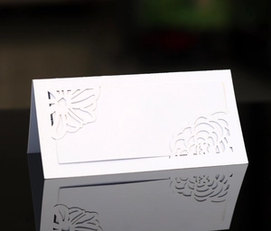 Detailed close-up of white laser-cut floral place card on black reflective surface