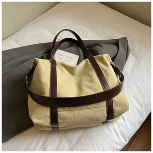 Detail of canvas tote bag with brown leather straps and side metal buckles on white fabric