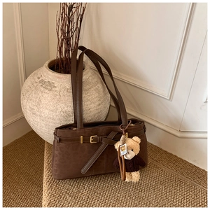 Close-up of leopard print suede bucket bag with decorative buckle and bear charm