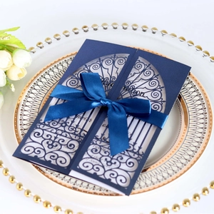 Élégante invitation de mariage bleu marine découpée au laser avec ruban sur une assiette