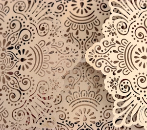 Detailed macro view of laser-cut mandala patterns on premium champagne gold invitations
