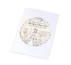 Detail of laser-cut white wedding invitation with floral patterns and couple silhouette