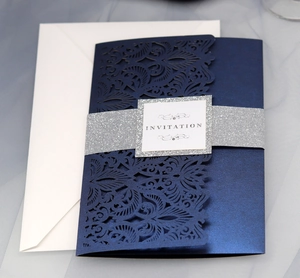 Navy blue laser-cut wedding invitation with silver glitter belly band and white envelope
