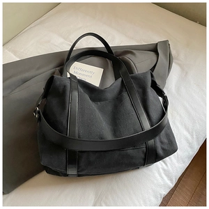 Close-up of the black canvas tote bag showing thick fabric texture and PU leather straps