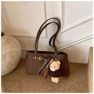 Detail of vintage leopard print bucket bag with gold hardware and teddy bear charm