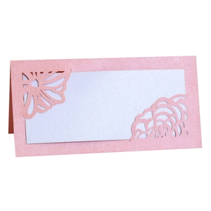 Macro detail of laser-cut hollow rose pattern on pink pearlescent paper wedding place card
