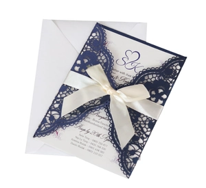 Navy blue laser-cut wedding invitation with white ribbon bow and inner card set