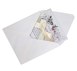 Détail d'une invitation de mariage découpée au laser avec dentelle et ruban de satin crème