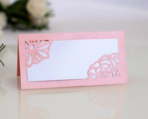 Macro view of pink laser-cut place card with elegant floral hollow patterns and pearl finish