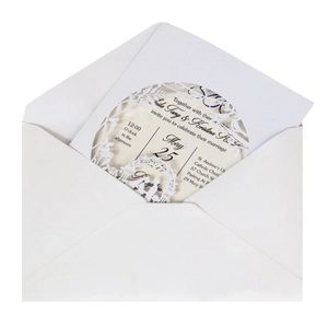 Close-up of white laser-cut wedding invitation featuring elegant floral and bird patterns