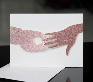 Laser cut glitter wedding invitation with hand and ring design and a white envelope