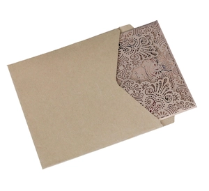Close-up of laser-cut hollow floral pattern on a vintage kraft paper wedding invitation