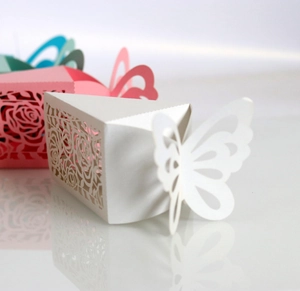 Detail of hollow laser-cut rose patterns and 3D butterfly closure on wedding candy boxes