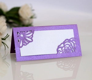 Detail of purple laser-cut wedding place card with glitter finish and elegant flower patterns