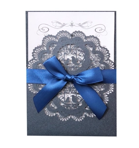 Detail of laser-cut lace wedding invitation with grey pearl paper and blue ribbon