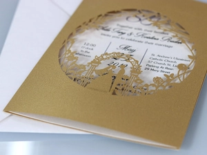 Detailed view of laser-cut gold wedding invitation featuring garden silhouettes and florals