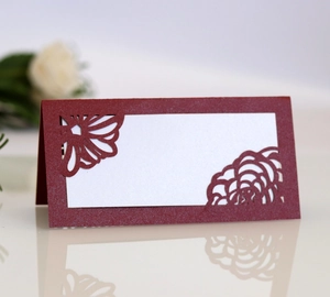 Macro shot of laser-cut burgundy table place card with intricate floral cutouts and white insert