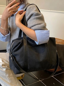 Large capacity black canvas tote bag with leather handles shown in a lifestyle setting