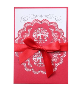 Detail of red laser-cut lace wedding invitation with birds and white inner card