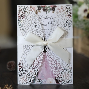 Detail of laser-cut wedding invitation with vine patterns and cream velvet ribbon