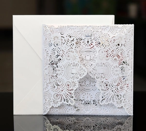 Detailed laser-cut mandala pattern on elegant white invitation sleeve and envelope