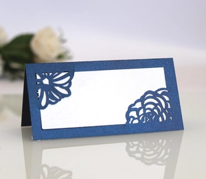 Detail of dark blue laser-cut wedding place card with elegant floral hollow pattern