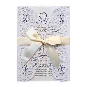Elegant white laser-cut floral wedding invitation card with a beige satin bow accent