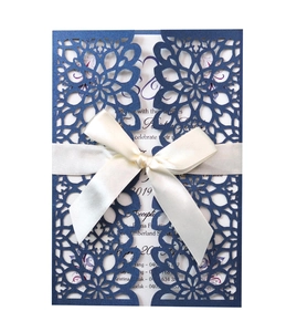 Detail of laser-cut navy blue wedding invitation with a silk cream ribbon bow