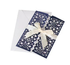 Detailed laser-cut floral pattern on navy invitation with cream ribbon and white envelope