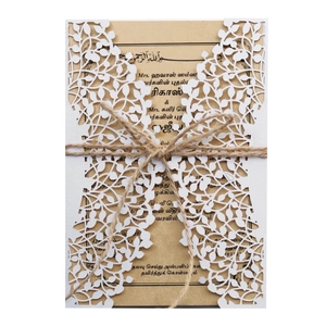 Detail of laser-cut floral white card with kraft insert and rustic twine bow tie