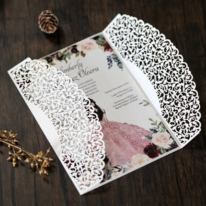 Close-up of laser-cut wedding invitation with intricate lace floral patterns and pink inner card