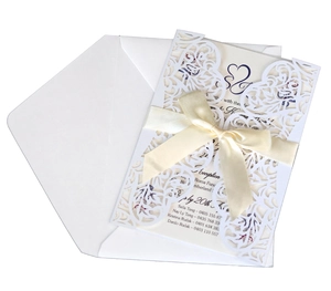 Elegant white laser cut wedding invitations with beige satin ribbon bow and envelopes