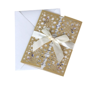 Detail of laser-cut floral wedding invitation with cream sleeve and white silk ribbon bow