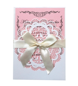 Detail of pink wedding card with laser-cut lace sleeve and cream satin ribbon bow