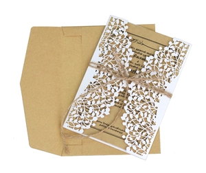 Detail of laser-cut leaf pattern on kraft paper wedding invitation with jute twine decoration